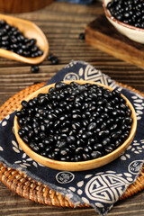 Black beans in wooden bowl on rustic wood table - healthy legume grains cooking ingredients