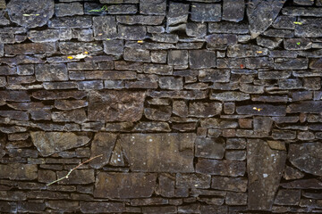 Reflection of a textured stone wall in still water