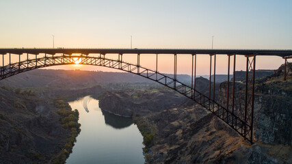 A bridge spans a river with a sunset in the background