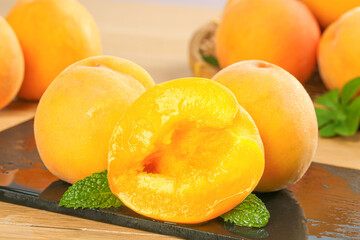 Fresh Yellow Peaches Cut in Half on Wooden Board with Mint Leaves - Sweet Summer Stone Fruit © HoangVan