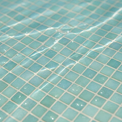 Blue mosaic tiles underwater in swimming pool with sunlight reflections and ripples