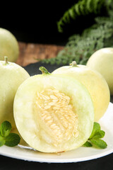 Fresh Cut Honeydew Melon Halves with Mint Garnish on White Plate