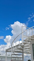 Naklejka premium Outdoor spiral staircase with blue sky.