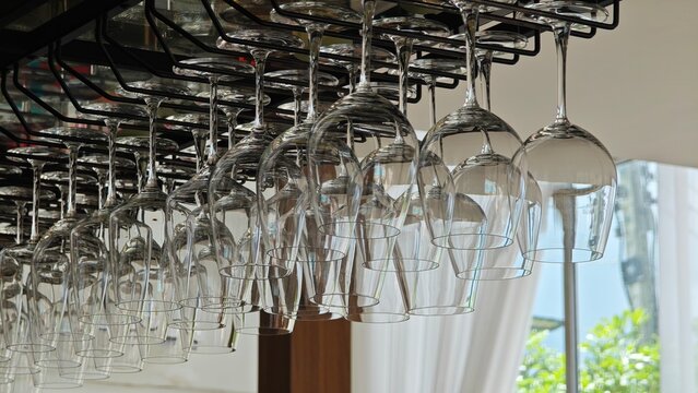 Wine glasses hanging in holder. Bar racks. - Powered by Adobe