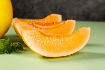 Fresh Yellow Honeydew Melon Slices with Orange Flesh on Green Background