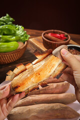 Fresh Sweet Potato Strips and Roasted Pieces with Hands Holding Golden Flesh Vegetables on Wooden Table