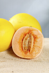 Golden honeydew melon cut in half showing fresh orange flesh and seeds on neutral background