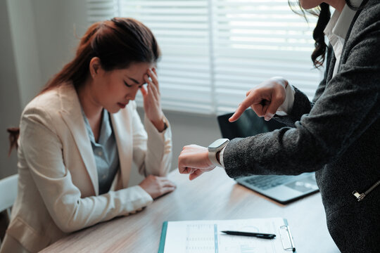 Stressed employee suffering headache while manager pointing at smartwatch and blaming her for being late at work