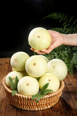 Small Fragrant Yunnan White Melons in Wicker Basket on Wooden Table with Hand Display