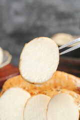 Fresh white radish slice held with kitchen tongs showing clean interior texture