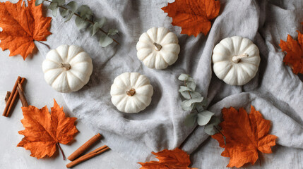 Top-Down Flat Lay of Mini White Pumpkins, Maple Leaves, and Cinnamon Sticks on Gray Linen Cloth