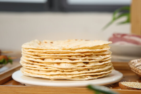 Stack of Thin Wheat Pancakes or Crepes on White Plate in Kitchen