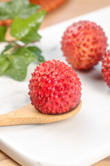 Fresh Lychee Fruits from Guangzhou Maoming China on Wooden Spoon with Green Leaves