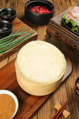 Chinese Dumpling Wrappers in Bamboo Steamer with Hot Pot Ingredients on Wooden Table