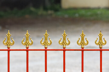 Metal fence or railing topped with trident (Trishul) finials.