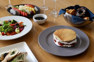Breakfast spread on a restaurant or cafe table including pancake, salad, fruits etc