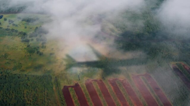 Shadow of the airplane with galo. Aircraft flies in the sky and casts the shadow on the land and clouds with strong galo effect