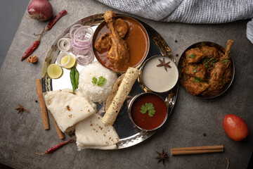 Kolhapuri chicken Thali is a popular Indian asian food platter consists of poultry meat, chikan sukka bhakri, rice, salad tambda padhra rassa 