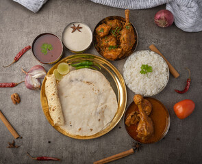 Kolhapuri chicken Thali is a popular Indian asian food platter consists of poultry meat, chikan sukka bhakri, rice, salad tambda padhra rassa 