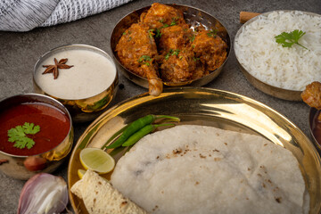 Kolhapuri chicken Thali is a popular Indian asian food platter consists of poultry meat, chikan sukka bhakri, rice, salad tambda padhra rassa 