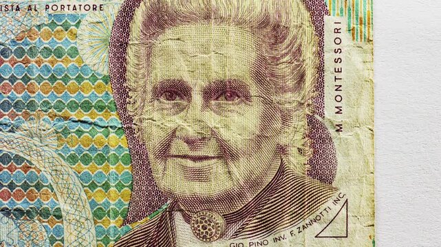 Close pan of an Italian 1000 lire note showing portrait, Italian text and deep folds