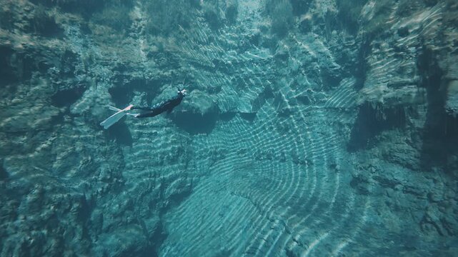 Freediver in the karst lake. Woman freediver swims underwater in the crystal clear lake named Goluboye Ozero near the city of Samara, Russia