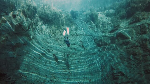 Freediver in the karst lake. Woman freediver swims underwater in the crystal clear lake named Goluboye Ozero near the city of Samara, Russia