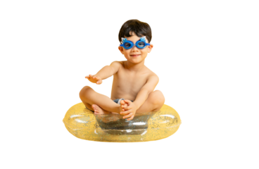 Asian A cheerful young boy with swimming goggles sitting in a yellow inflatable pool float on PNG