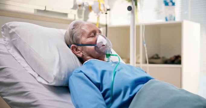 Sick, senior patient and oxygen mask in hospital bed for respiratory support, ventilation or coma. Healthcare, elderly woman or sleeping with respirator in intensive care for surgery recovery or rest