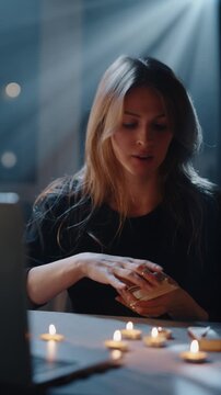 Young woman shuffling tarot cards during mystical ritual with candles