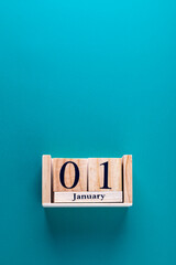 Vertical close-up shot of wooden calendar blocks with date January 01 on blue background. Copy space. Concept of first day, new year and new challenges