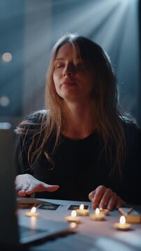 Young woman performing tarot reading ritual with candles indoors