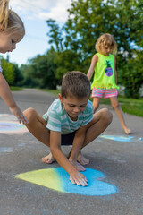 Fototapeta premium Children draw a heart with chalk and color it in blue and yellow.