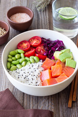 Poke bowl with rice, salmon, avocado, red cabbage, edamame and tomatoes. Healthy food. Diet.