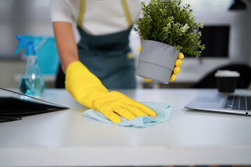 young woman in yellow gloves cleaning the table in the office