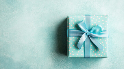 A light blue gift box with white polka dots and a light blue ribbon sits on a light blue background