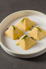 Four pyramid shaped herb cheese bites served with chives