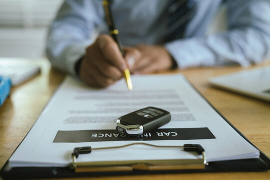 A business agent finalizes a car agreement, with documents, keys, and signature symbolizing insurance, finance, legal contract, and vehicle ownership.