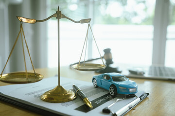 A symbolic scene featuring the scales of justice, a car, a hammer and contract documents representing law, insurance, judgment and legal liability in the event of an accident.