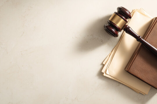 Wooden gavel resting on a leather law book and stacked legal documents on marble &mdash; courtroom justice theme, judgment, authority and legal concept background