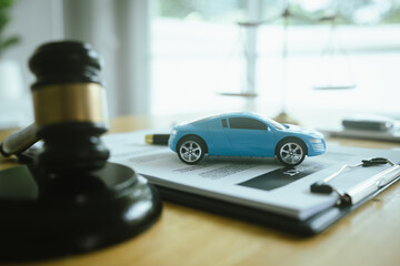 A symbolic scene featuring the scales of justice, a car, a hammer and contract documents...