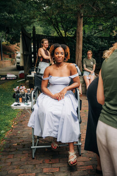 Actress sitting in director chair getting makeup done outdoors