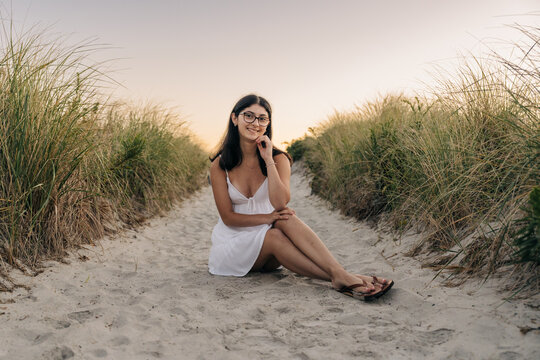 Young woman relaxing on sandy path at sunset beach