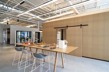 Modern office space with a long table, stools and glass partitions
