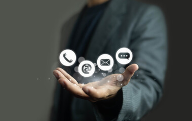 Businessman holding digital communication icons including phone, email, chat, and at symbol. Concept for customer support, contact us, online service, messaging, and business connection.
