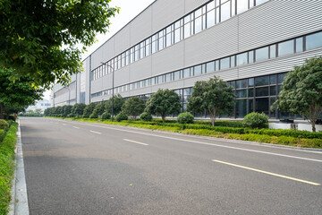 Obraz premium Modern building with glass facade, greenery, and empty road