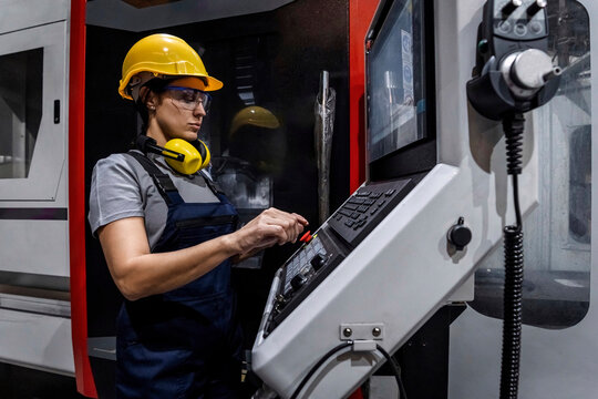 Engineer wearing hardhat operating CNC machine in modern factory