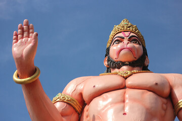 Mighty Hanuman statue, powerful Hindu god of strength and devotion, low angle shot against blue sky