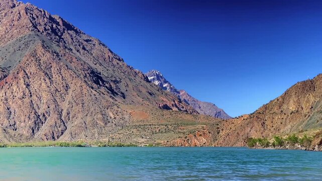 View of the most beautiful lake in Tajikistan - Iskanderkul mountain lake on the northern slopes of the Gissar range in the Fan Mountains. A journey through Asia