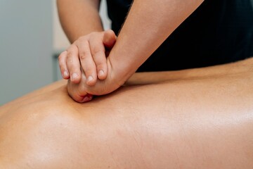 Deep tissue massage therapist pressing on back with hands